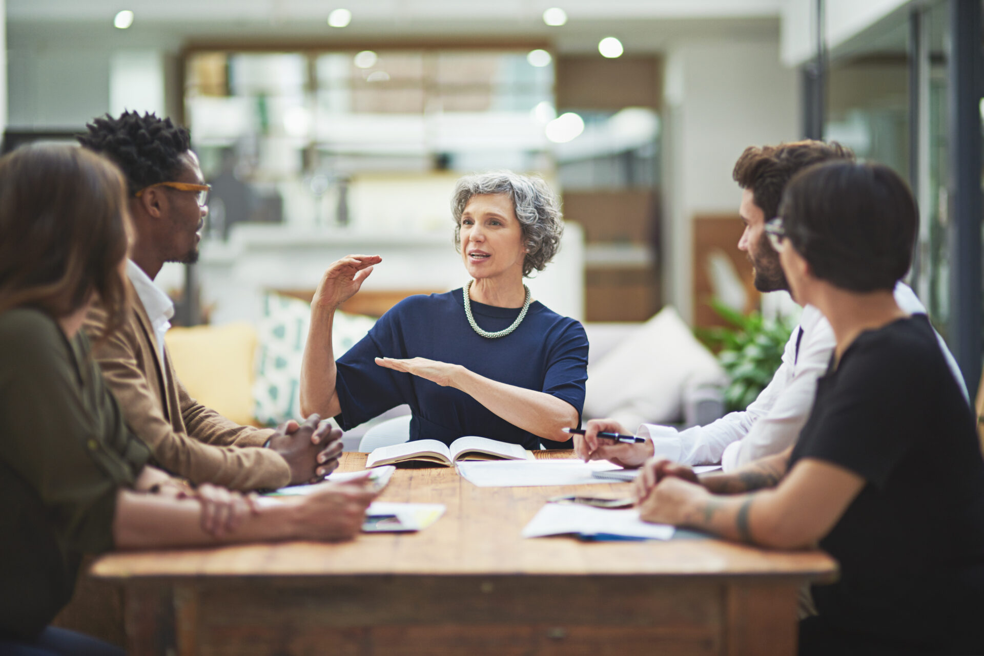 Mature, woman and presentation for mentor, work and company in office for colleagues in business. Female professional, talking and coworkers in meeting for brainstorming, ideas and vision in startup