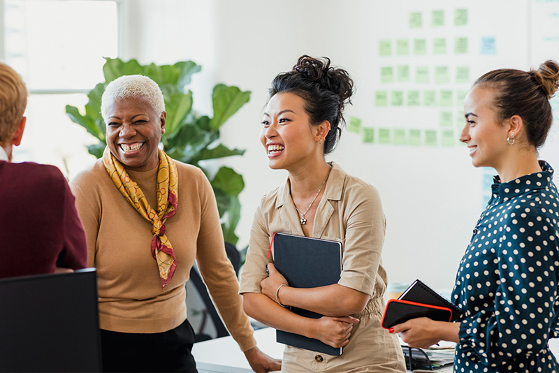 a group of female coworkers standing and casually laughing